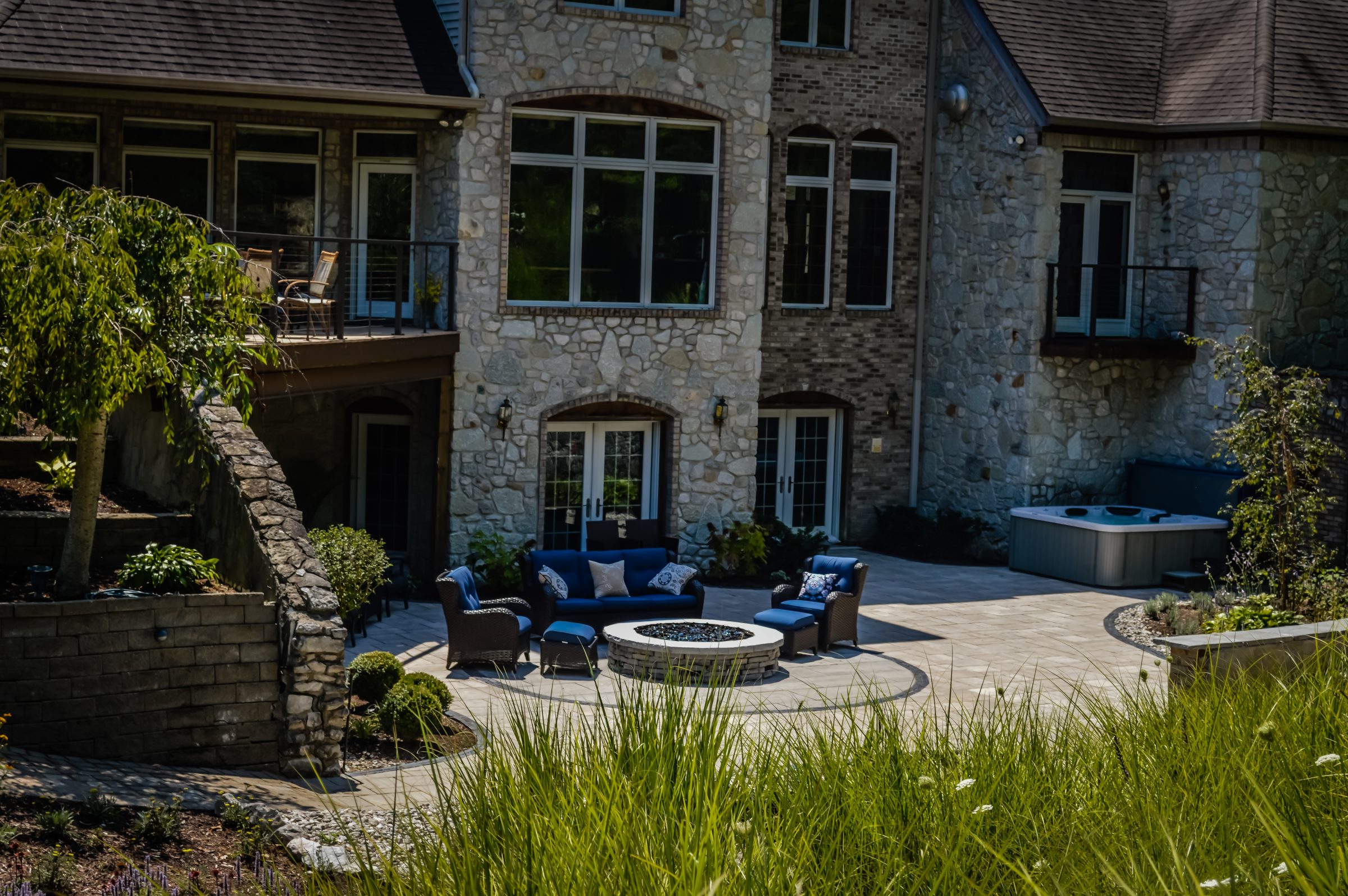 Stone house patio with outdoor furniture and hot tub