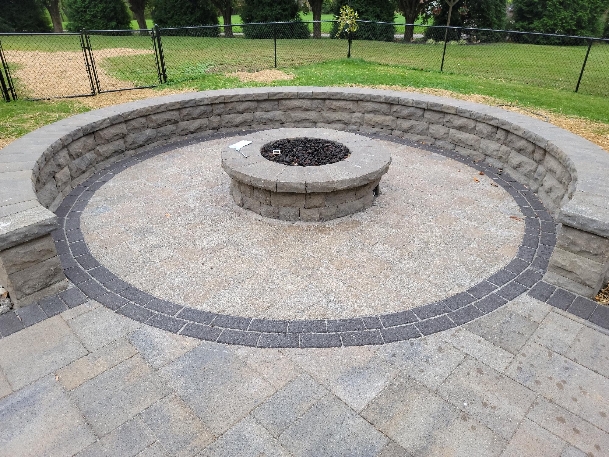 Outdoor stone fire pit with circular seating.
