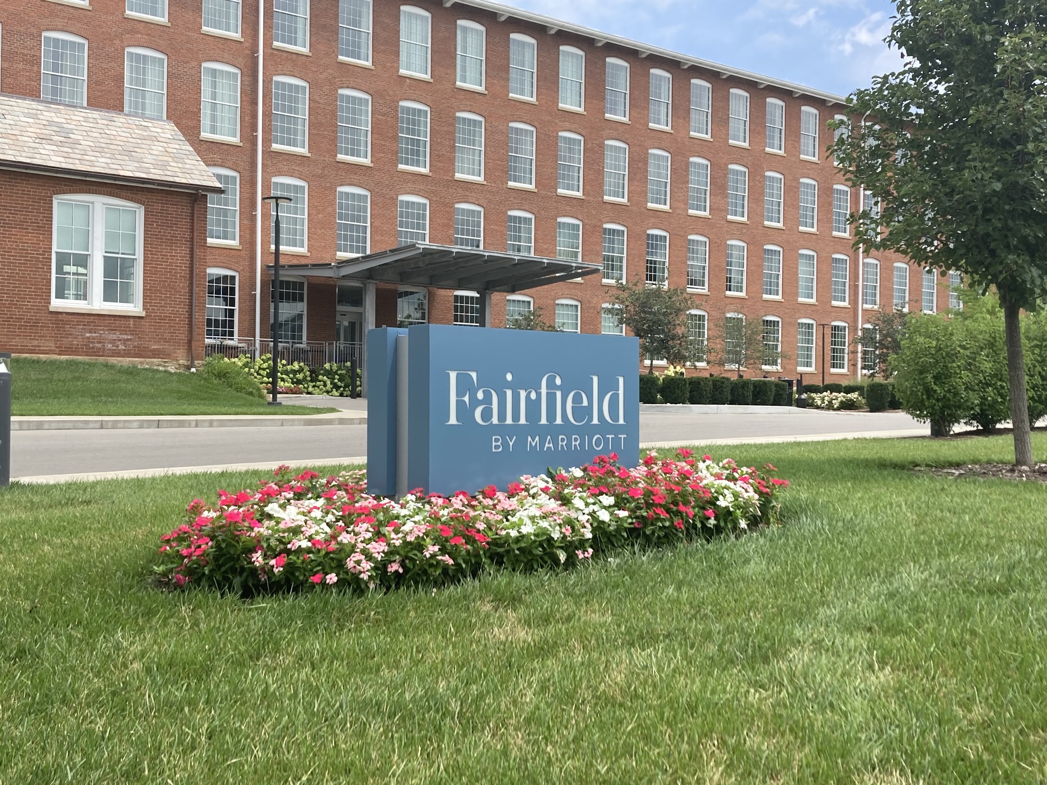 Fairfield by Marriott hotel entrance with sign and flowers.