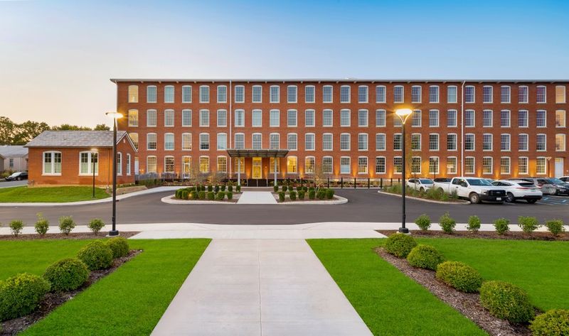 Historic brick building with green lawn and parking.