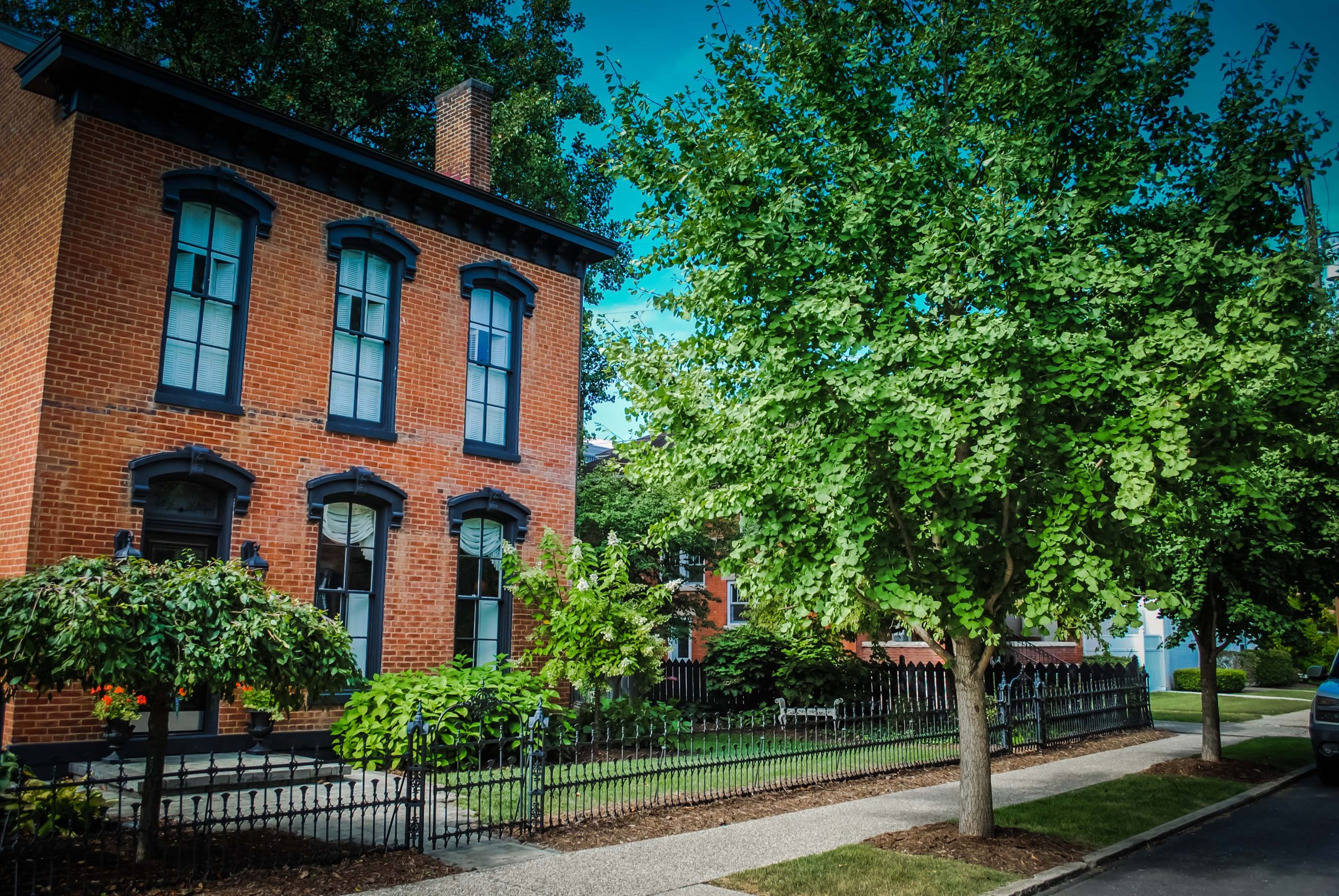 Historic brick home with black trim and garden.