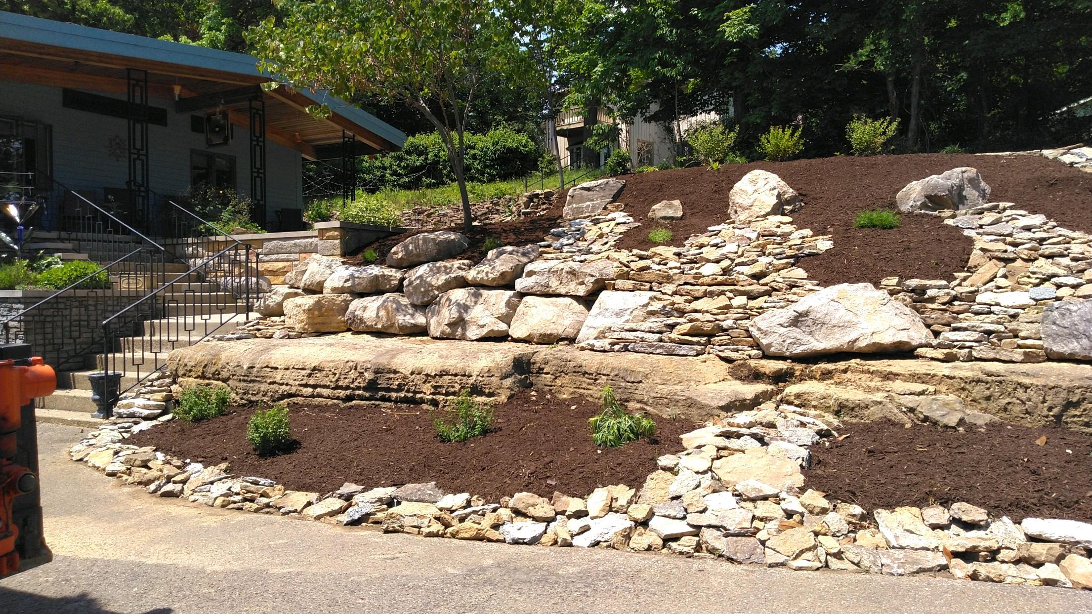Terraced rock landscaping around house entrance.