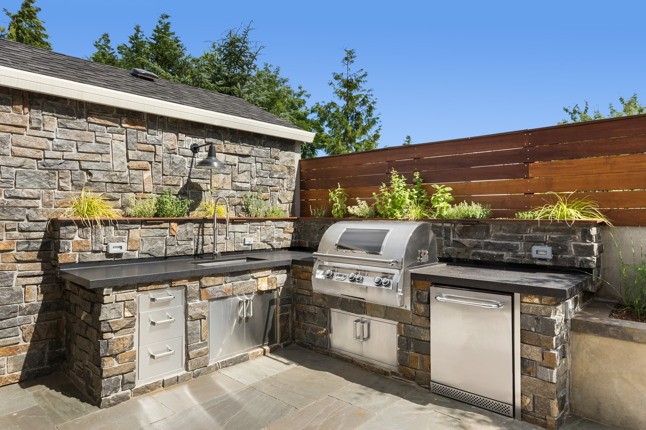 Modern outdoor kitchen with grill and stone design.
