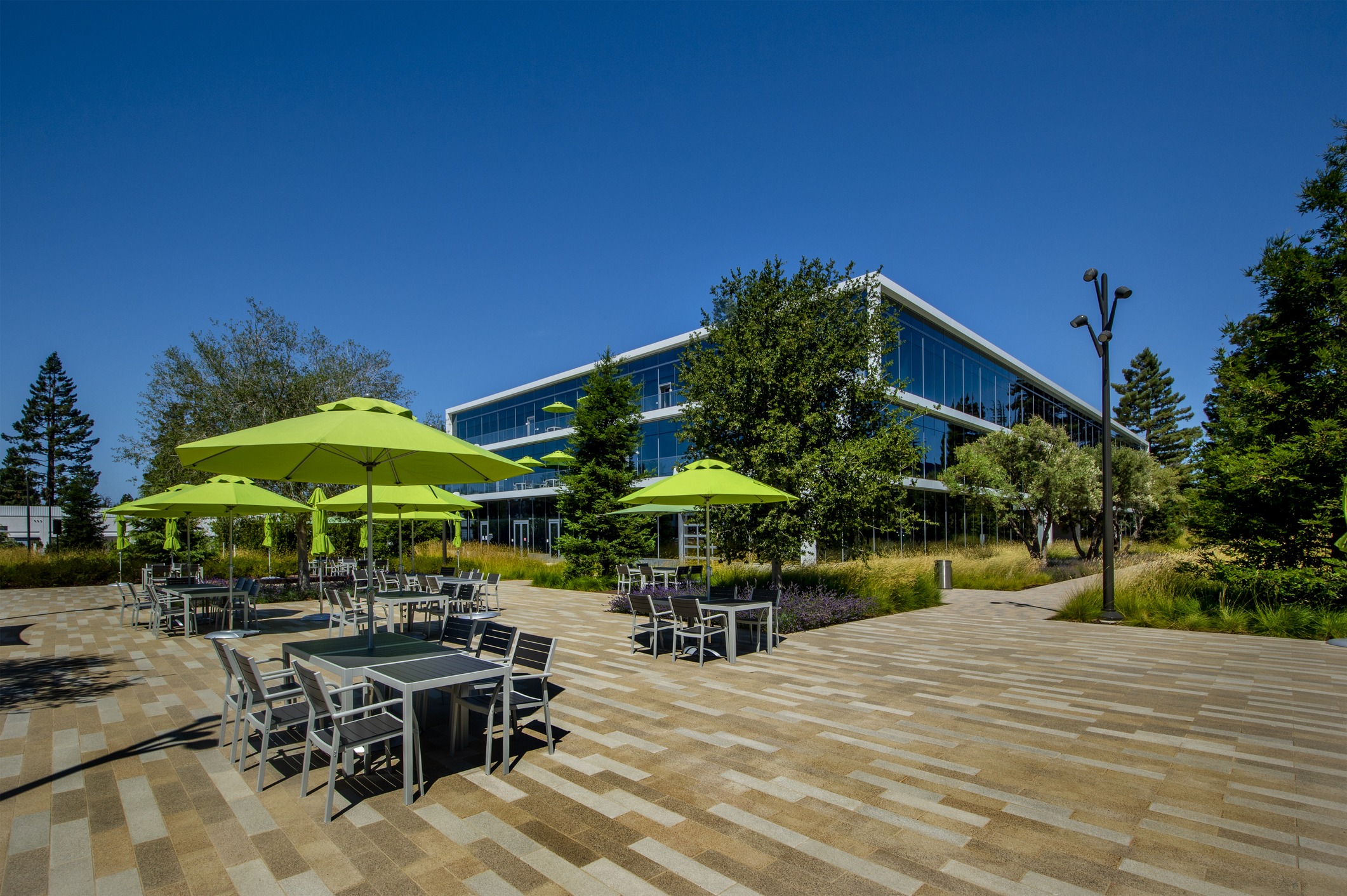 Modern building with outdoor seating and green umbrellas.