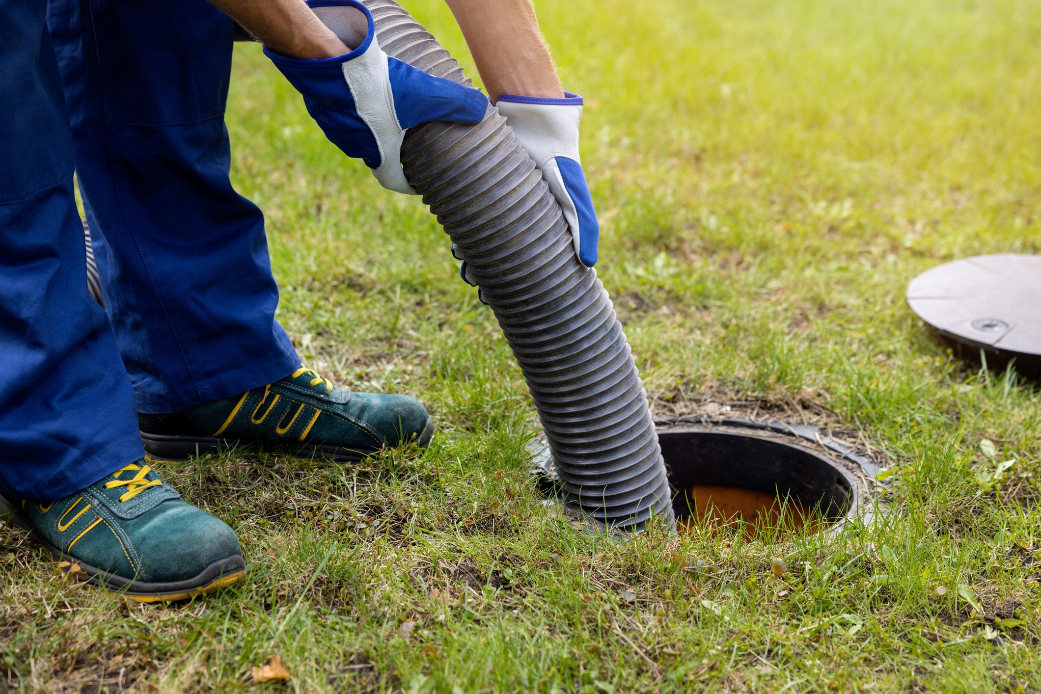 Worker using hose for septic tank maintenance