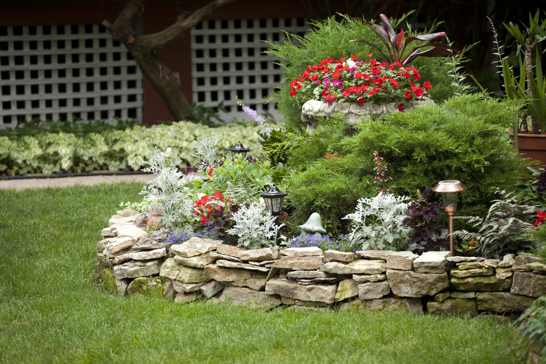 Colorful garden with stone border and lanterns.