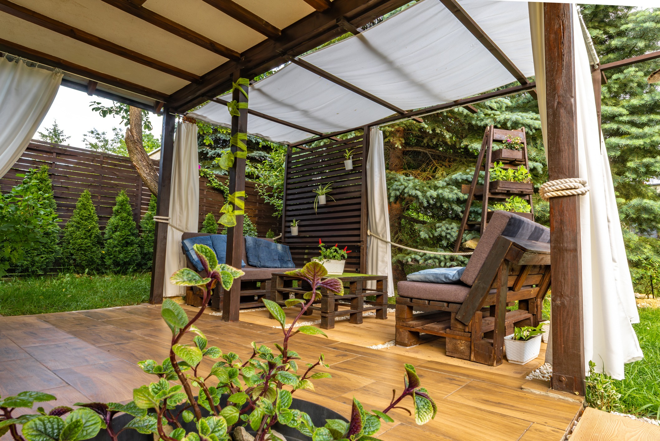 Cozy wooden patio with plants and seating area.