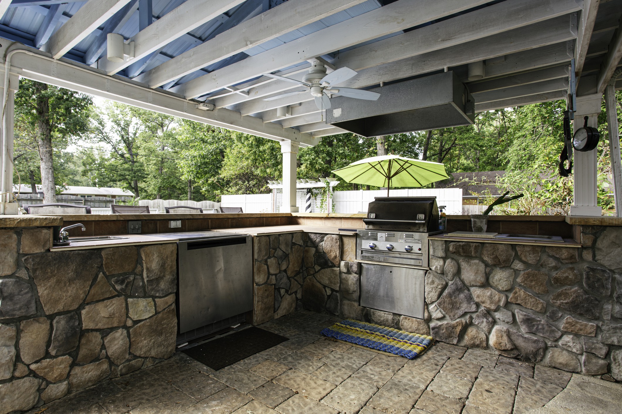 Outdoor kitchen with stone counters and barbecue grill.
