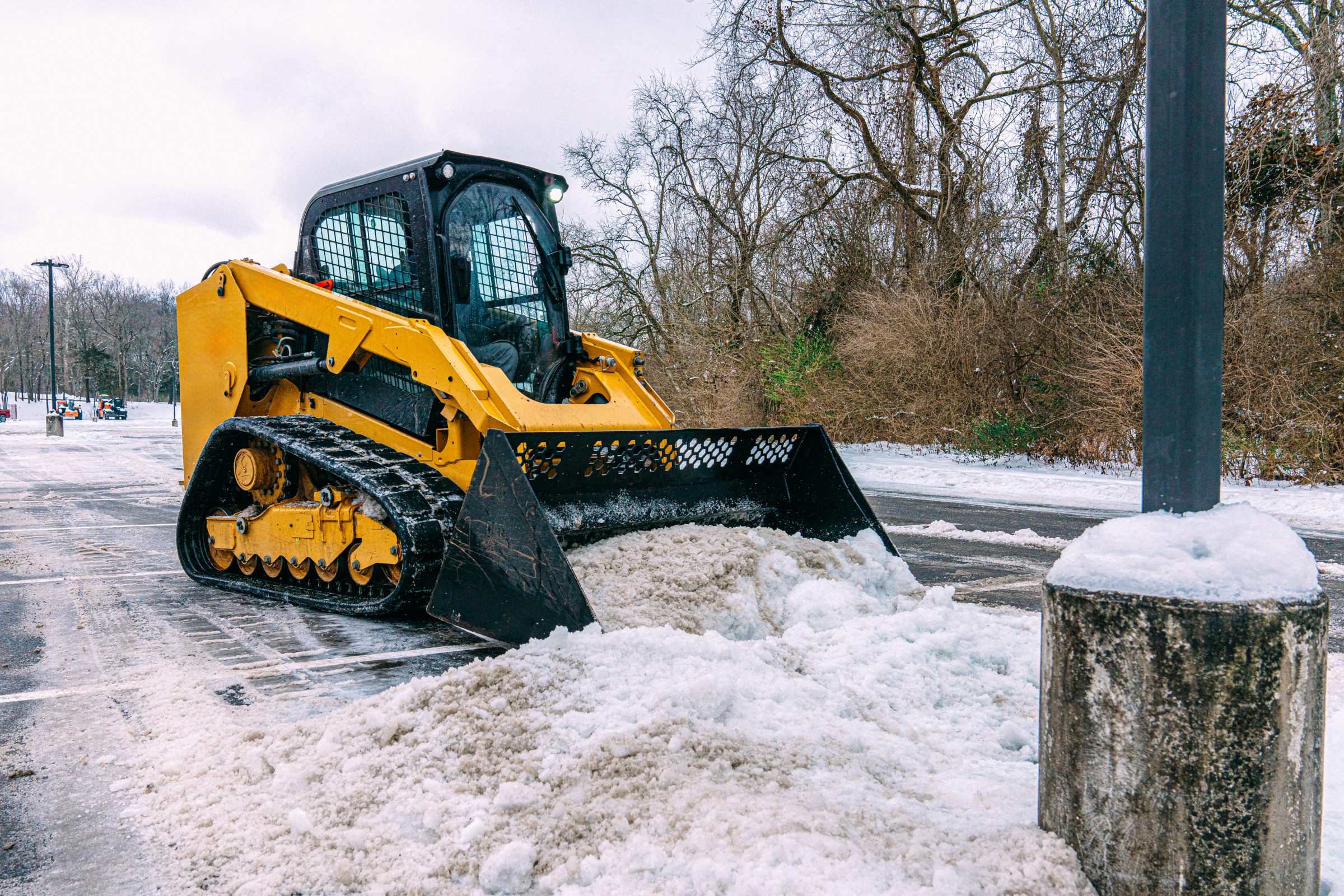 Bulldozer clearing snow in winter parking lot.
