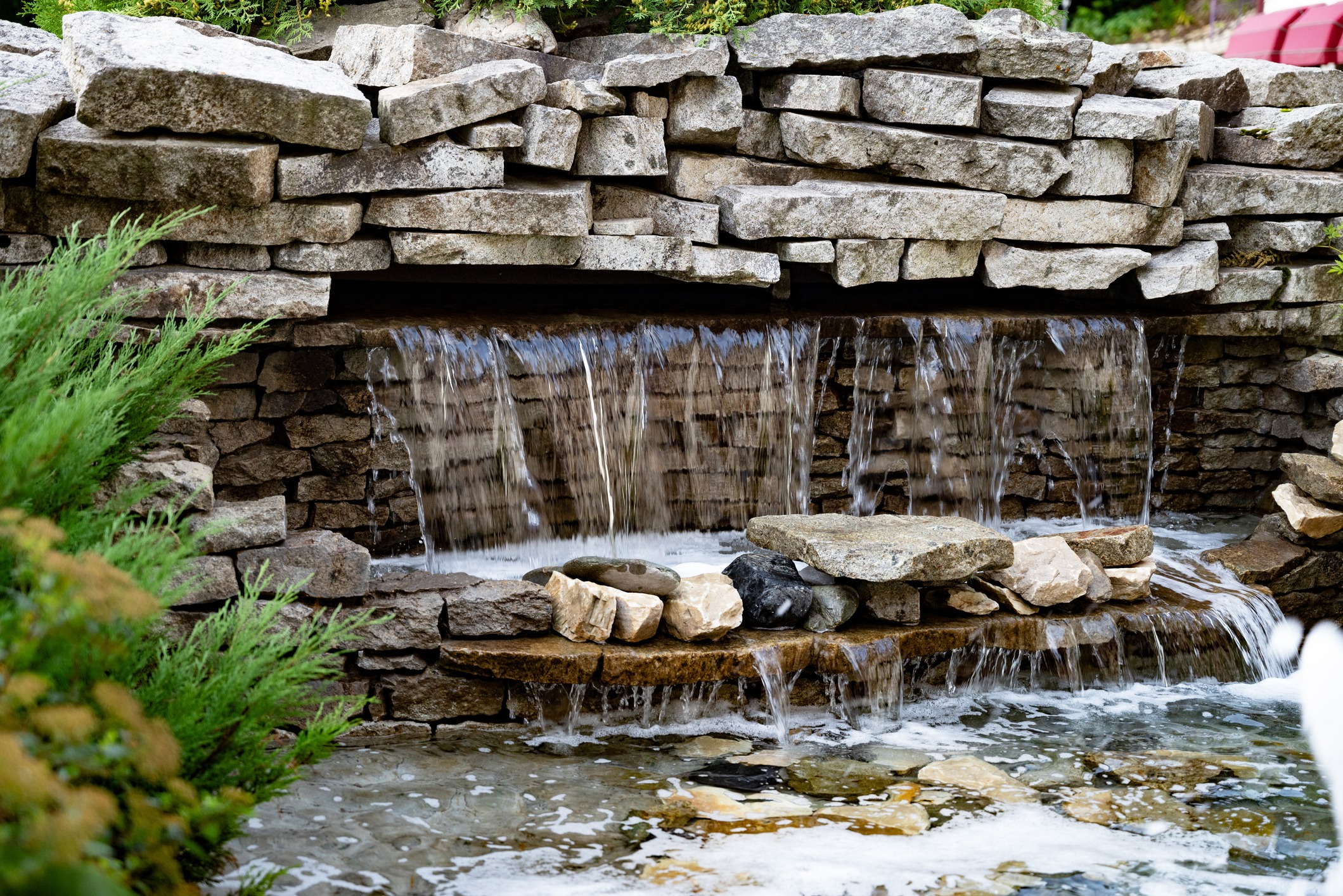 Stone waterfall with cascading water in garden