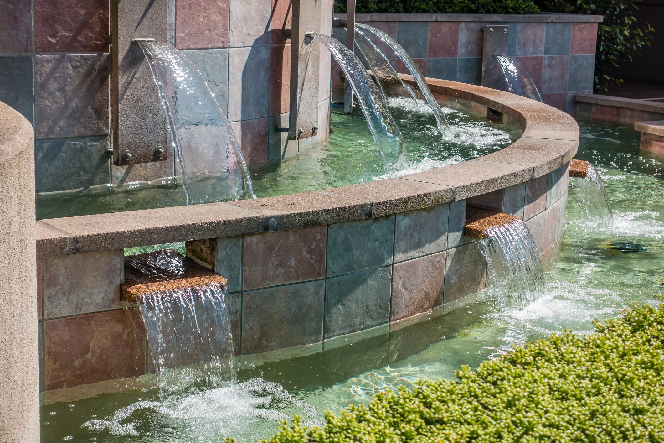 Curved tile fountain with flowing water streams.