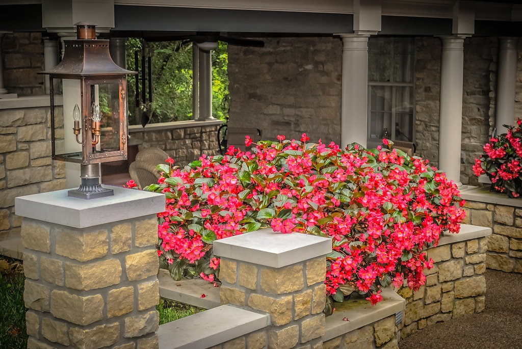Stone porch with red flowers and lantern.