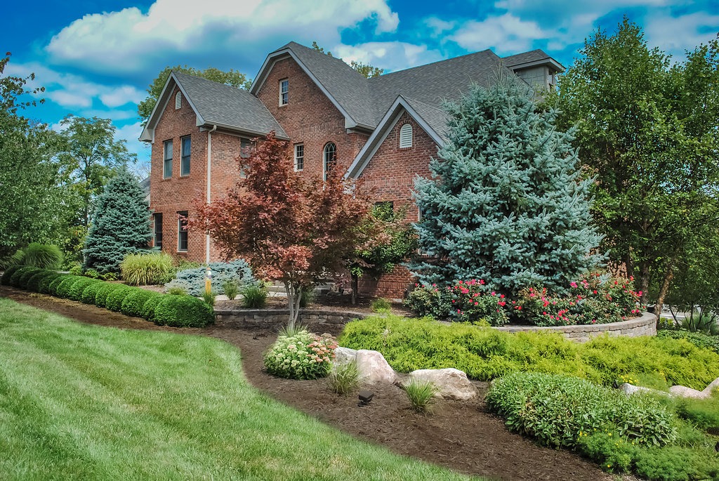 Red brick house with lush garden landscaping.