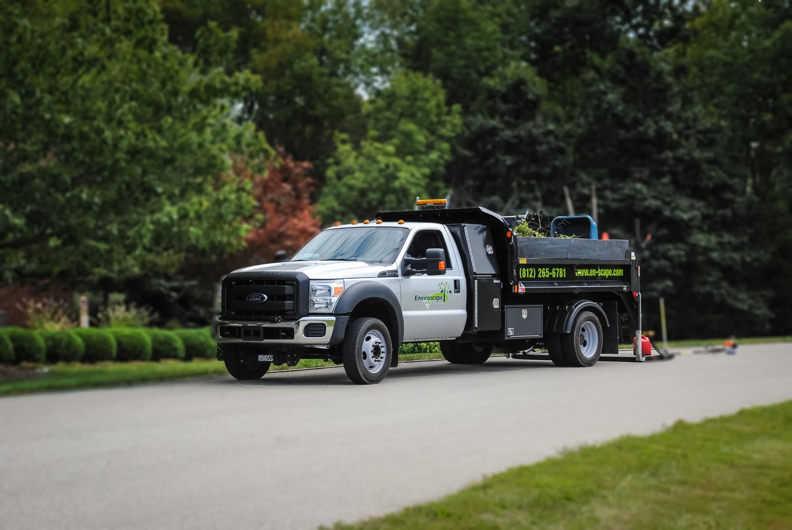 Landscaping truck with equipment on road.